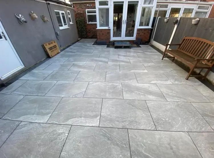 Grey porcelain paved patio with a garden bench